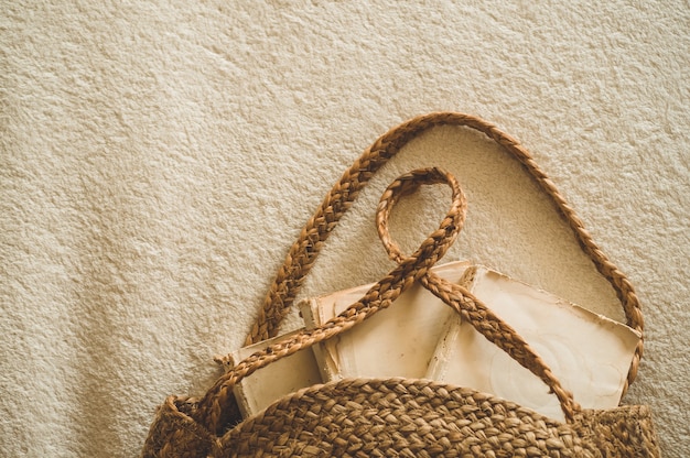 Oude boeken en vintage strozak op witte warme deken. Tas stro zomer vrouw. Bruine handgemaakte natuurtas.