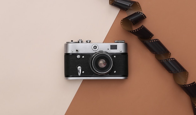 Oude camera met filmband op beige-bruine achtergrond. Bovenaanzicht