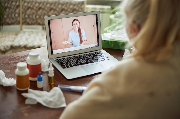 Oude dame met griep die online overleg heeft met arts thuis