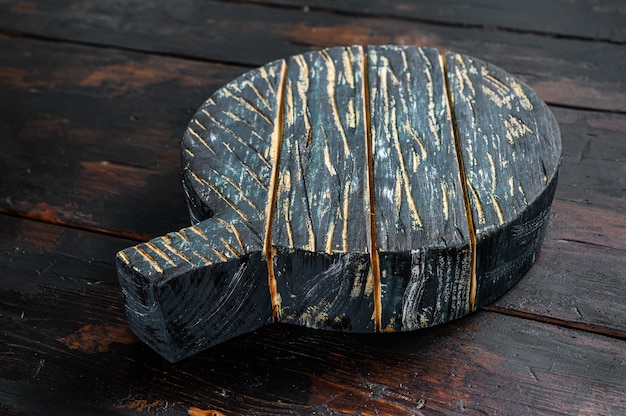 Oude donkere snijplank op bruin houten tafel. Donkere achtergrond. Bovenaanzicht. Kopieer ruimte.