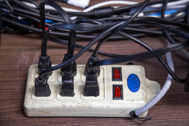 Oude en beschadigde stekker van de elektrische adapter heeft veel apparaten die zijn aangesloten op het stopcontact