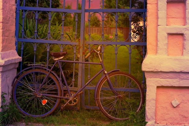 Oude fiets geparkeerd bij het hek