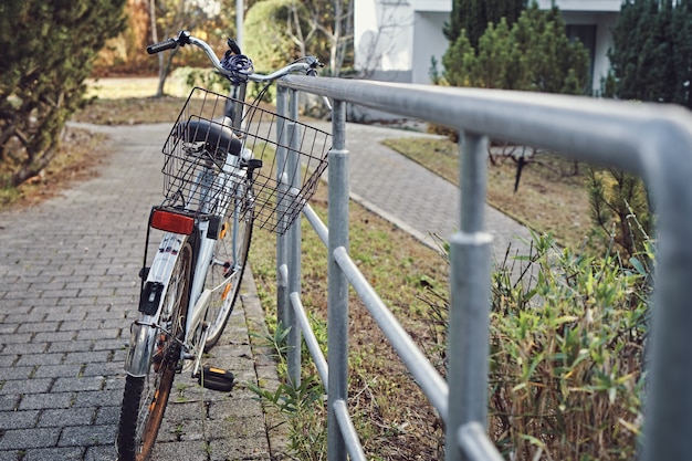 Oude fiets met roest geparkeerd op een reling in de stad. Transport en stadsleven