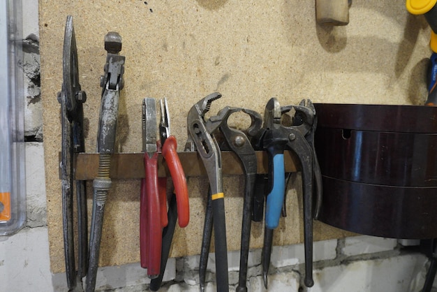 Oude gereedschappen hangen aan de muur in de werkplaats Gereedschapsplank tegen een muur