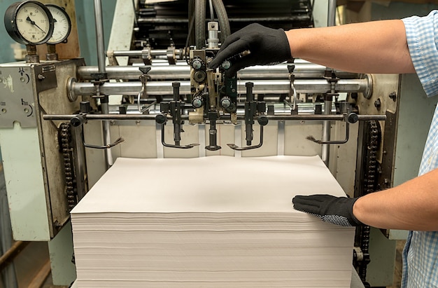 Oude grootformaat drukpers. De handen van de vrouw houden papier vast.