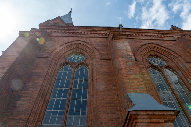 Oude historische gotische katholieke kathedraal gemaakt van rode baksteen Uitzicht op de kathedraal van onderaf tegen de achtergrond van de zon en de blauwe lucht