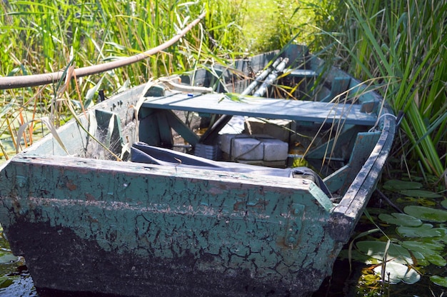 Oude houten armoedige vervallen kapotte boot om te zwemmen aan de oevers van de rivier de zee van het meer