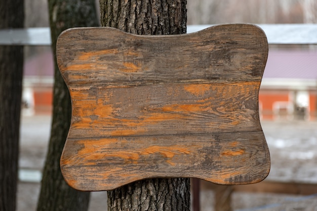 Oude houten bord op boom. Ruw geschaafd houten oppervlak. Kopieer ruimte.