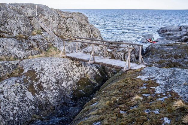 Oude houten brug en trappen op rotsachtig eiland en twee kajaks geparkeerd op het strand