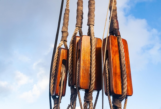 Oude houten katrollen van een zeilschip met geknoopte touwen tegen de lucht