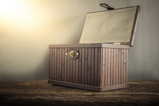 Oude houten kist met open aangestoken op houten tafelblad tegen grungemuur