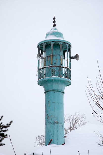 Oude houten minaret in de winterdag