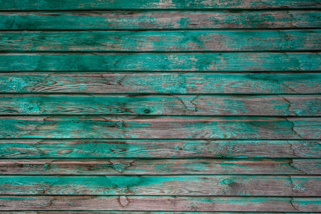 Oude houten planken met afbladderende groene verf. De groene verf komt van de houten planken. Groene verf met oud houten oppervlak