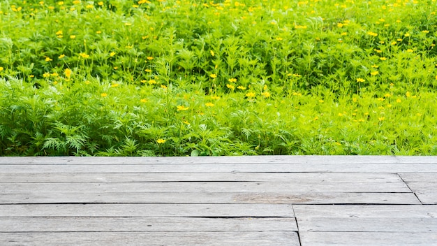 Oude houten vloer met gele kosmosbloemenvelden