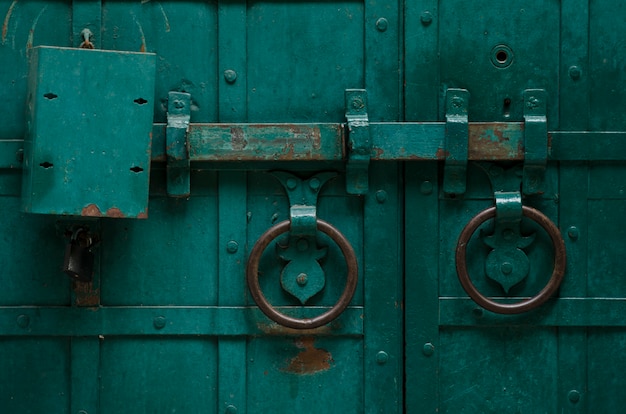 Oude ijzeren deur met grendel geschilderd met groene verf