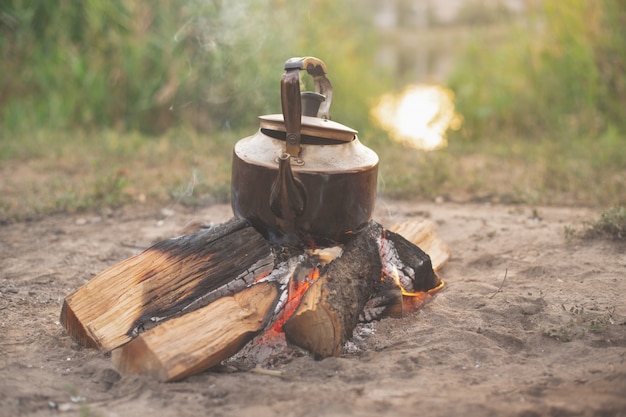 Oude ijzeren ketel staat op brandhout, camping