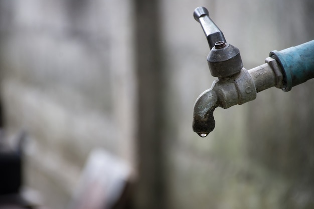 Oude kraan met water dat op de grond lekt.