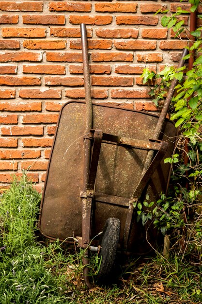 Foto oude kruiwagen die tegen bakstenen muur leunen