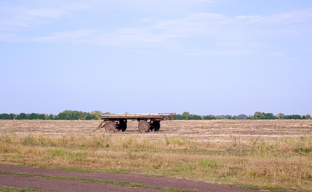 Oude lege kar voor het verzamelen van stro in het veld. Oogstapparatuur in een rustiek tarweveld.