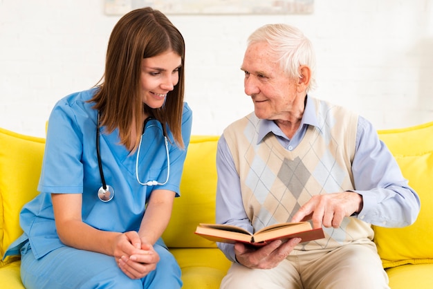 Oude man die op een boek met een verpleegster kijkt