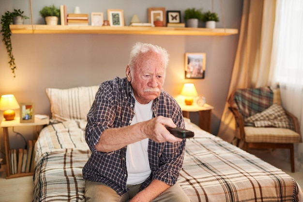 Oude man die tv kijkt tijdens zijn pensionering