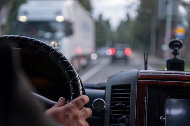 oude man handen tijdens het rijden op de weg met wazige lichten en auto's verkeer