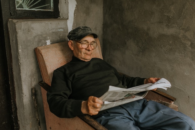 Oude man in glazen met grijs haar een krant lezen