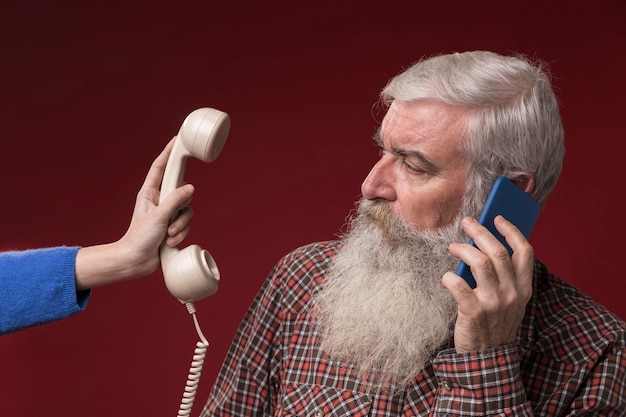 Oude man met nieuwe en oude telefoon