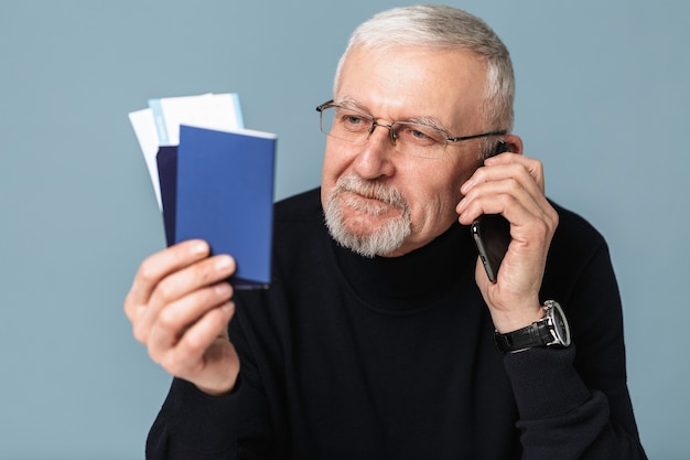 Oude man met vliegtuigtickets en paspoort portret