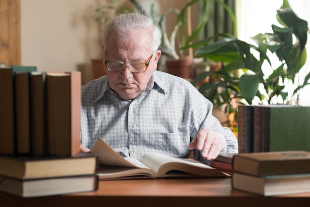 Oude man of grootvader die literatuur aan een bureau op kantoor leest