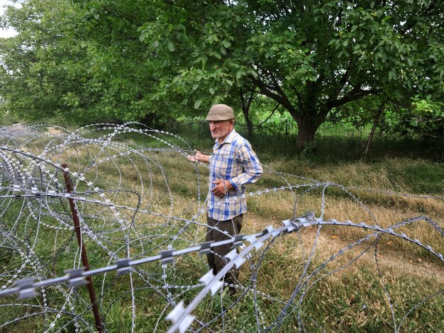 Oude man op lokale tribune bij prikkeldraad op de scheidingslijn met de bezette regio tskhinvali de feitelijke grens van georgië met zijn afgescheiden regio zuid-ossetië