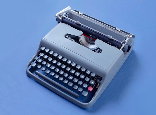 Oude matblauwe typemachine geïsoleerd op een effen groenblauw achtergrond met veel esthetiek