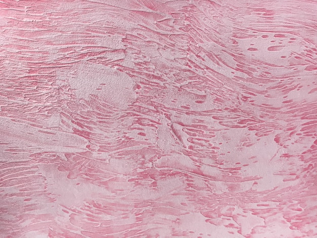 Oude muur bedekt met armoedige peeling gips. Textuur van uitstekende lichtrode en roze steenoppervlakte, close-up.