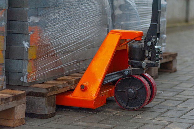 Oude oranje handmatige handpallettrucks Close-up wiel van hydraulische handpallettruck