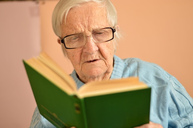 Foto oude oudere vrouw van 90 jaar met een open papierboek in haar handen die een bestseller roman concept leest