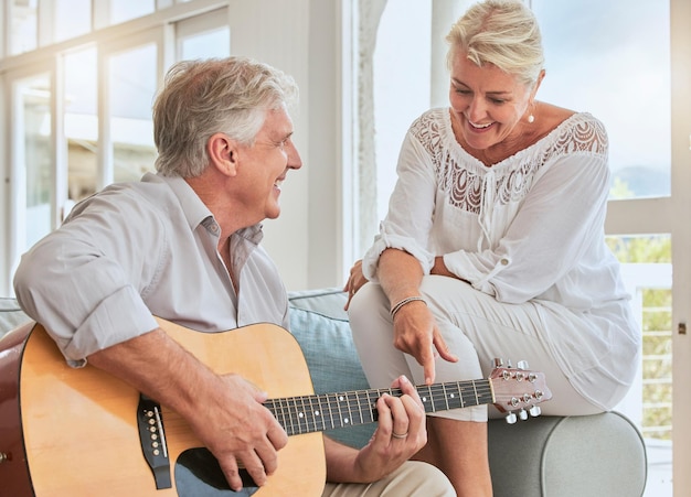 Oude paar gitaar en liefde in huisbank of bank die een romantisch lieftallig of genegenheid muzikaal lied voor vrouw speelt Romance gepensioneerde senior man en vrouw spelen akoestisch snaarinstrument in woonkamer