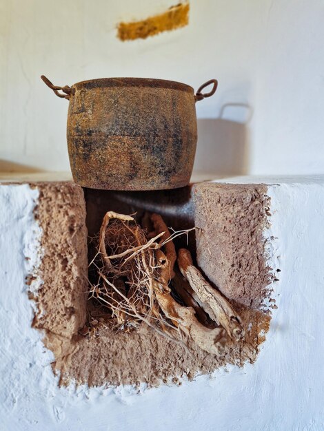 Oude pot met wortels van ginseng op een witte muur.