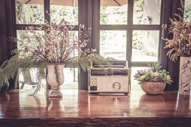 Oude radio en gedroogde bloem in vaas op houten tafel