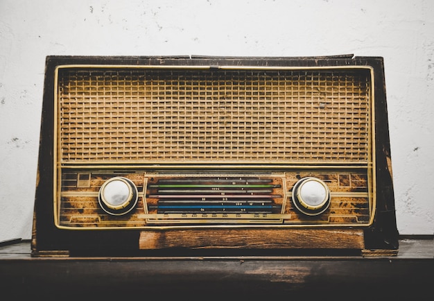 Oude retro houten radio-ontvanger op houten tafel met witte grunge cement gips muur achtergrond