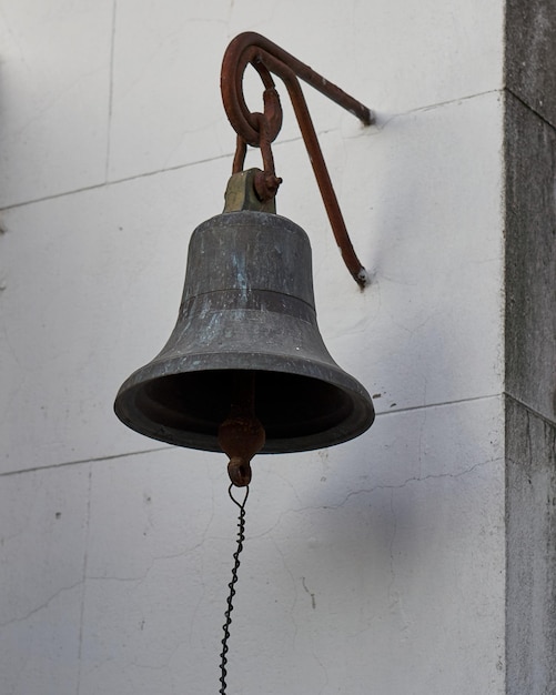 Oude roestige bel die aan een muur hangt