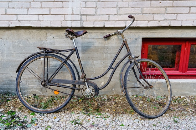 Oude roestige fiets geparkeerd op de muur van een oud gebouw.