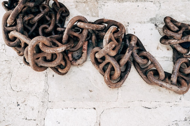 Oude roestige ketting op een stenen oppervlak verschillende schakels van een roestige oude ketting