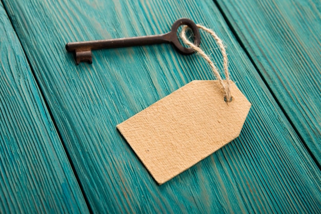 Oude roestige sleutel met een papieren label op het houten bord