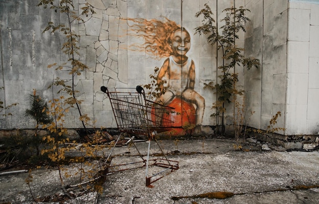 Oude roestige trolley van supermarkt in de uitsluitingszone van Tsjernobyl met ruïnes van de verlaten pripyat-stadszone van de spookstad van radioactiviteit