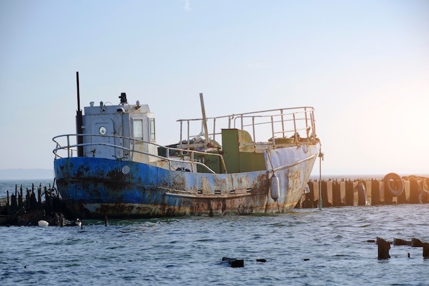 Oude roestige vissersboot gedokt verwoeste pier