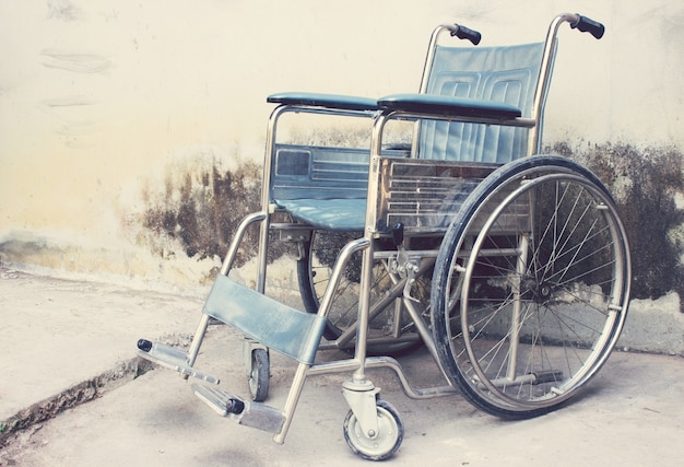 Oude rolstoelen met muur achtergrond
