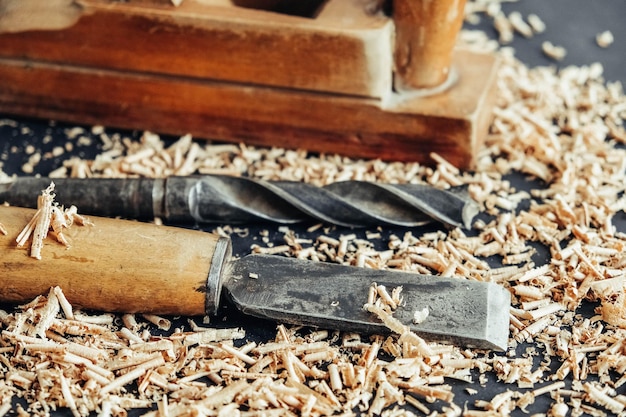 Oude rot vliegtuig, boor en beitel met houten schaafsel op zwarte achtergrond. oude houtbewerking handgereedschap. kopiëren, lege ruimte voor tekst