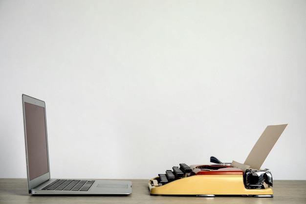 Oude schrijfmachine en laptop op tafel tegen lichte achtergrondruimte voor tekst Concept van technologische vooruitgang