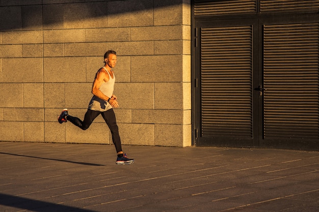 Oude sportman die op landweg loopt