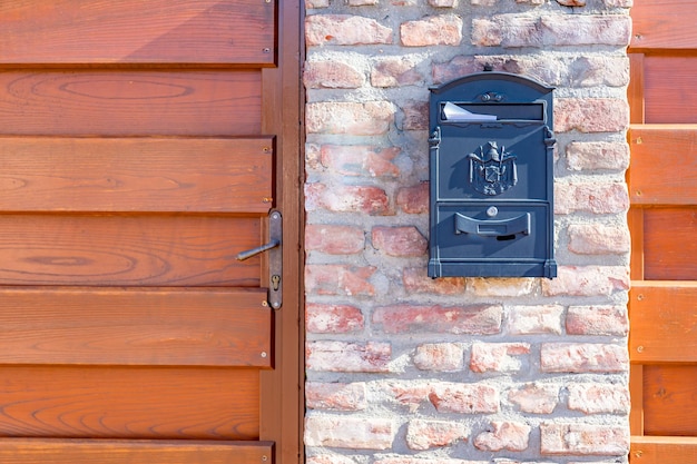 Oude stalen, ijzeren brievenbus op stenen muur, naast houten hek op gebouw of huisdeur. Huis